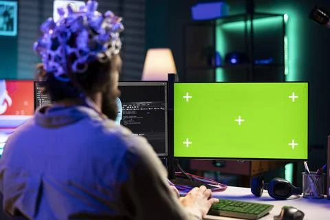 Man with EEG headset programs brain transfer into green screen computer Foto stock