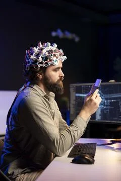 Man with EEG headset putting disk in computer to start consciousness upload Foto stock