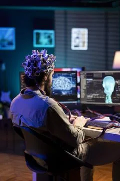 Man with EEG headset on writing code allowing him to transfer mind into computer Stock Photos