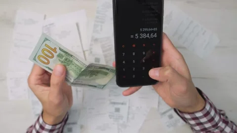 A man is efficiently managing his finances and payments by using his phone to Stock Footage 280307496