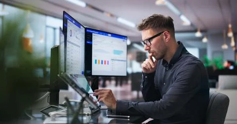 Man Efficiently Using Dual Touchscreen Laptops To Manage Maintenance Requests Stock Photos