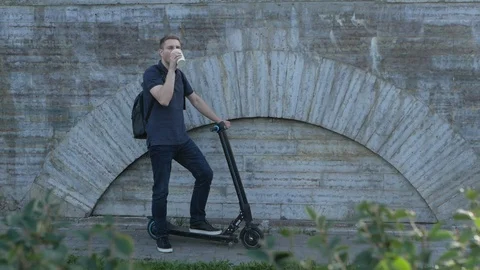 A man with electric scooter drinking coffee Video stock 115366755