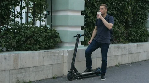 A man with electric scooter drinking coffee Stock Footage 115367184