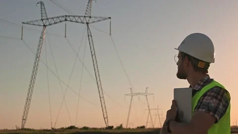 Man electrical engineer with beard adjusts his white safety helmet on his head Stockbeeldmateriaal 206033656