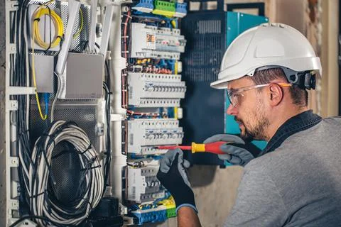Man, an electrical technician working in a switchboard with fuses. Stock Photos