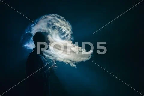 The man with an electronic cigarette on the dark background Stock Photos