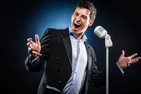 Man in elegant black jacket and blue shirt singing Stock Photos