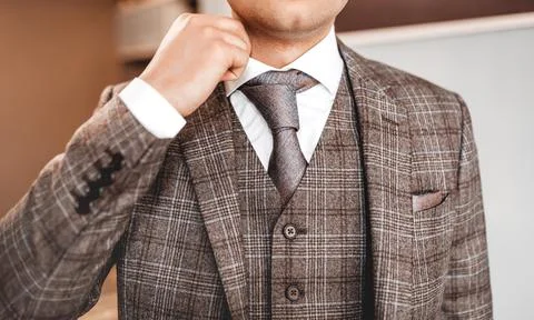 Man in elegant custom tailored expensive suit posing. Groom set the tie strai Stock Photos