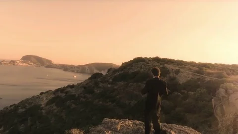 Man in elegant suit with briefcase walking on top of a cliff on an island Stock Footage