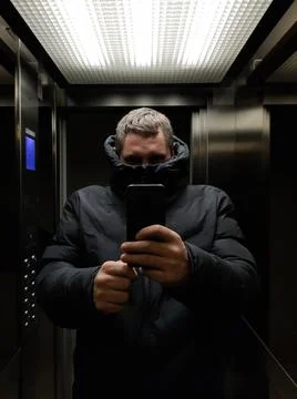 The man in the elevator put a jacket on his face Stock Photos