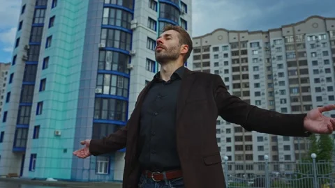Man embracing the moment in front of high-rise buildings at sunset Stock Footage 288183556
