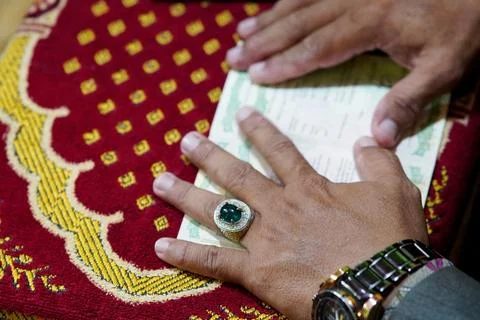 Man with emerald ring and watch reviews important document on decorative mat Foto stock