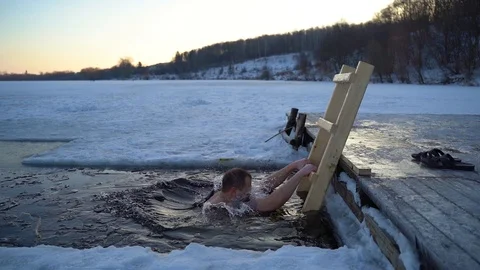 A man emerges from the cold water in an ice hole 100fps Video stock 101417008