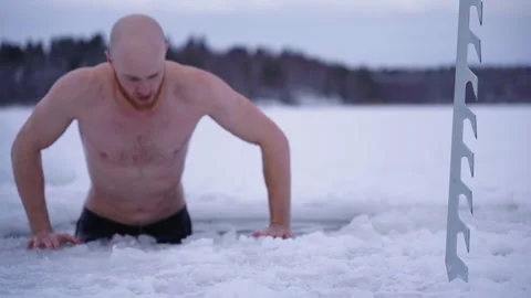 Man Emerging From Ice Hole During Cold Plunge in Frozen Lake Stock Footage 328498532