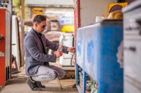 Man with an empty Coca Cola bottle  at a vintage vending machine Foto stock