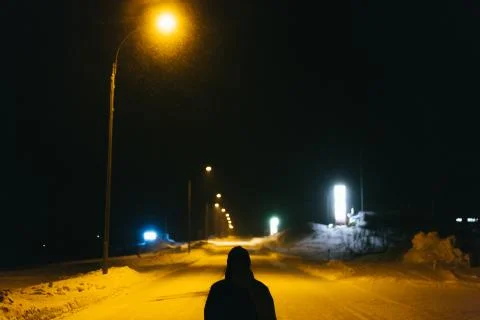 Man on empty road in night while snowing in winter Stock Photos