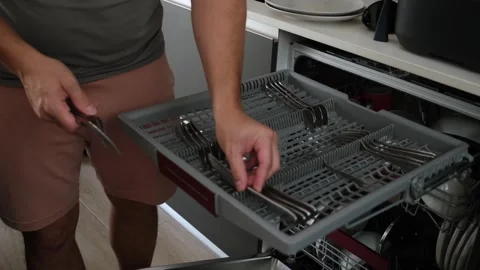 Man emptying clean silverware from a dishwasher cutlery tray Stock Footage 345733270