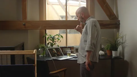 Man ends a video chat with a work colleague and picks up his cell phone Video stock 133295910