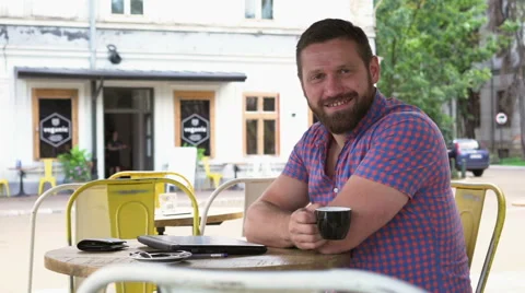 Man ends work on laptop, drinks coffee and smiles for camera in cafe Vídeos de archivo 67631604