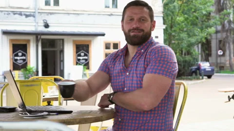 Man ends work on laptop, drinks coffee and smiles for camera in cafe, 库存影片 67632385
