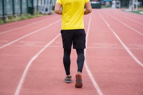 Man energetically jogging on stadium track, active and healthy lifestyle town Stock Photos