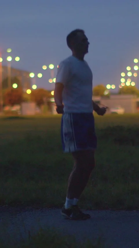 A man is energetically jumping rope in a park during the night Stock Footage 317340736