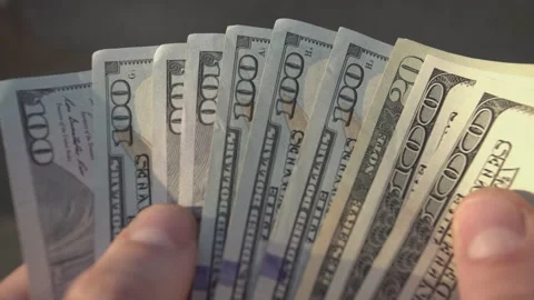 Man engaged in counting a stack of us dollar bills Stock Footage 296749214