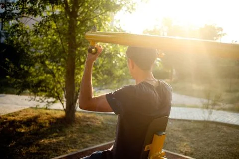 The man is engaged on the exercise machine, swings hands on the city street. Stock Photos