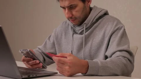 A man engaged with his phone and laptop for performing various online financial Video stock 319901778