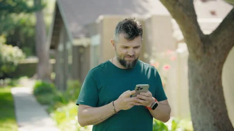 A man is engaged with his smartphone while enjoying a lush and vibrant outdoor Vídeos de archivo 285698159