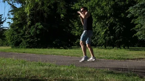 Man is engaged in kick boxing in the park Stock Footage 76817414