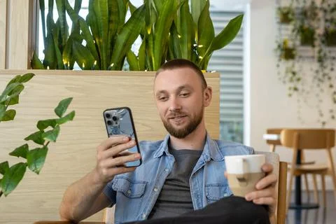 Man engaged in online education while sitting indoors with plants around an.. Stock Photos