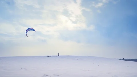 A man is engaged in snow kiting on a snowy hill in winter, jumping and enjoying Stock Footage 88094511