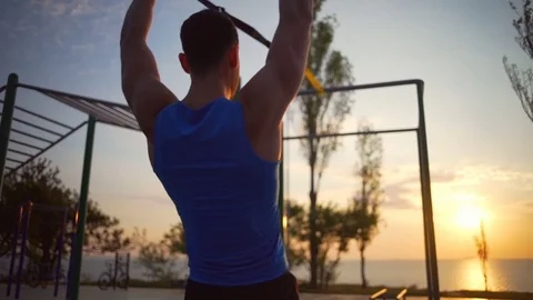 Man engaged in trx exercises pull up change hand workout outdoor dawn slowmotion Stock-Footage 76777964