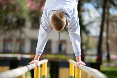 A man is engaged on the uneven bars. Do exercises on the street. Stock Photos