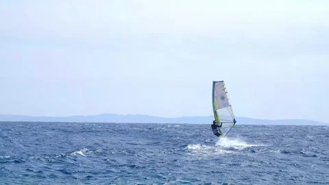 A man is engaged in windsurfing in the red sea, mountains in the background, wat Stock Footage 240199320