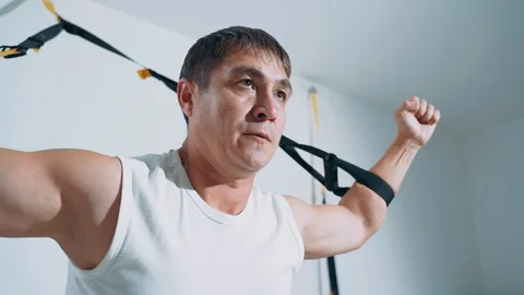 A man engages in the gym using TRX loops. Exercise on the muscles of the chest. Video stock 115122362