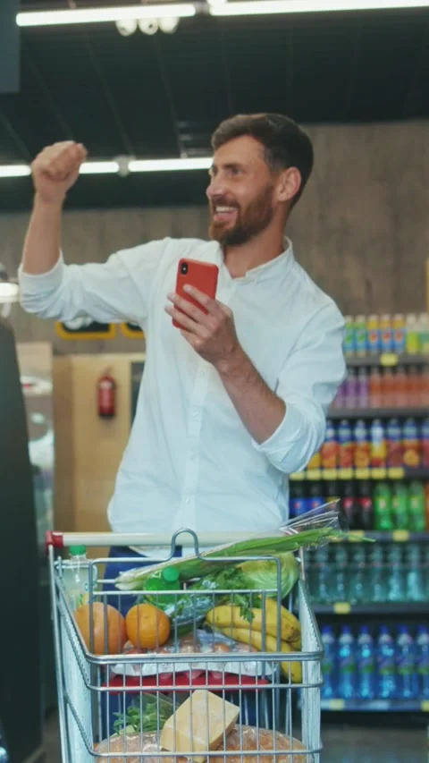 A man engaging in shopping activities with his smartphone while at a grocery Stock Footage 314206745