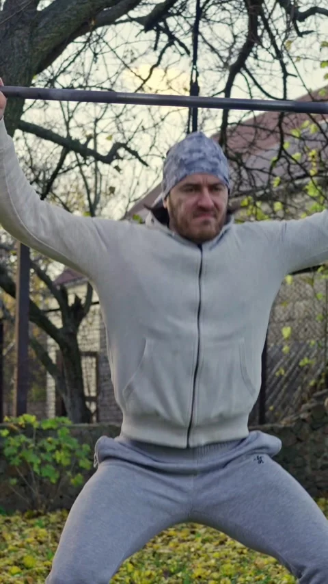 A Man Engaging in Strength Training Outdoors, Using Weights for His Workout Stock Footage 308588298