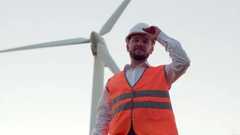 A man engineer with a beard in an orange vest adjusts a white helmet Stock Footage 136455754