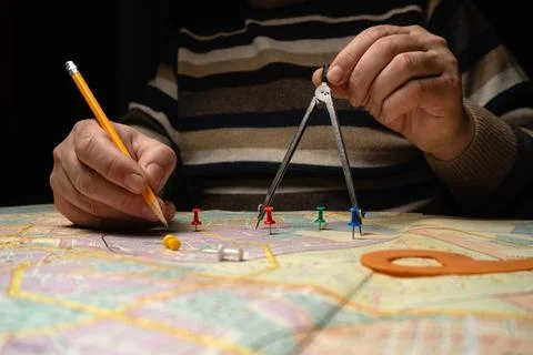 A man engineer is focused on a map, using a compass and pencil to draw line.. Stock Photos