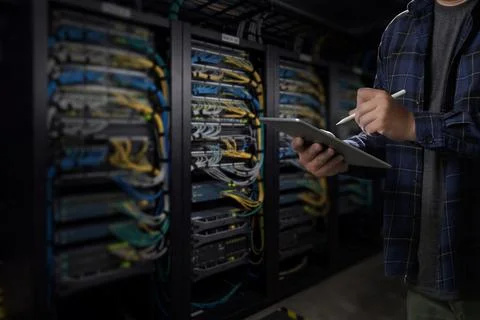 Man engineer it support using tablet and stylus beside server racks in a da.. Stock Photos