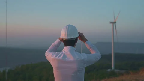A man engineer is putting a protective helmet on his head over electric turbi Vídeos de archivo 149050891