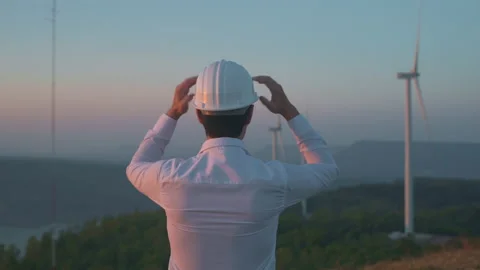 A man engineer is putting a protective helmet on his head over electric turbi Stock Footage 149051306