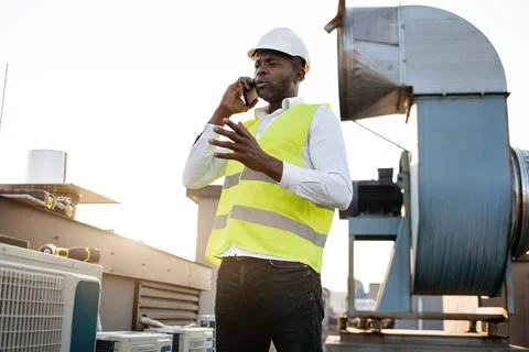 Man engineer standing and talking on smartphone on roof Stock Photos