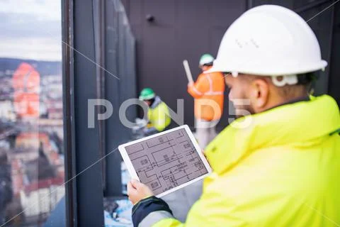 Man engineer standing on construction site, holding tablet. Stock Photos