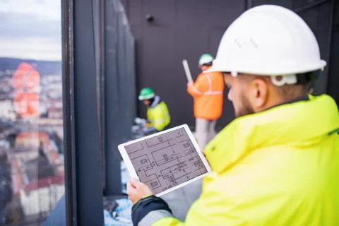 Man engineer standing on construction site, holding tablet. Stock Photos