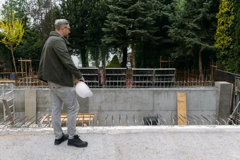 Man engineer standing on construction site looking on workers Stock Photos