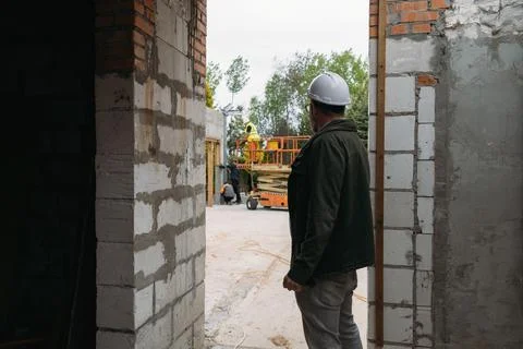 Man engineer standing on construction site looking on workers Stock Photos