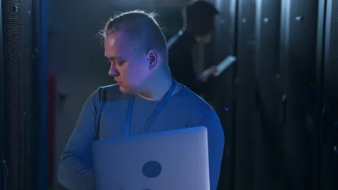 Man engineer using laptop and checking hardware, colleague working near at data Stock Footage 163816476